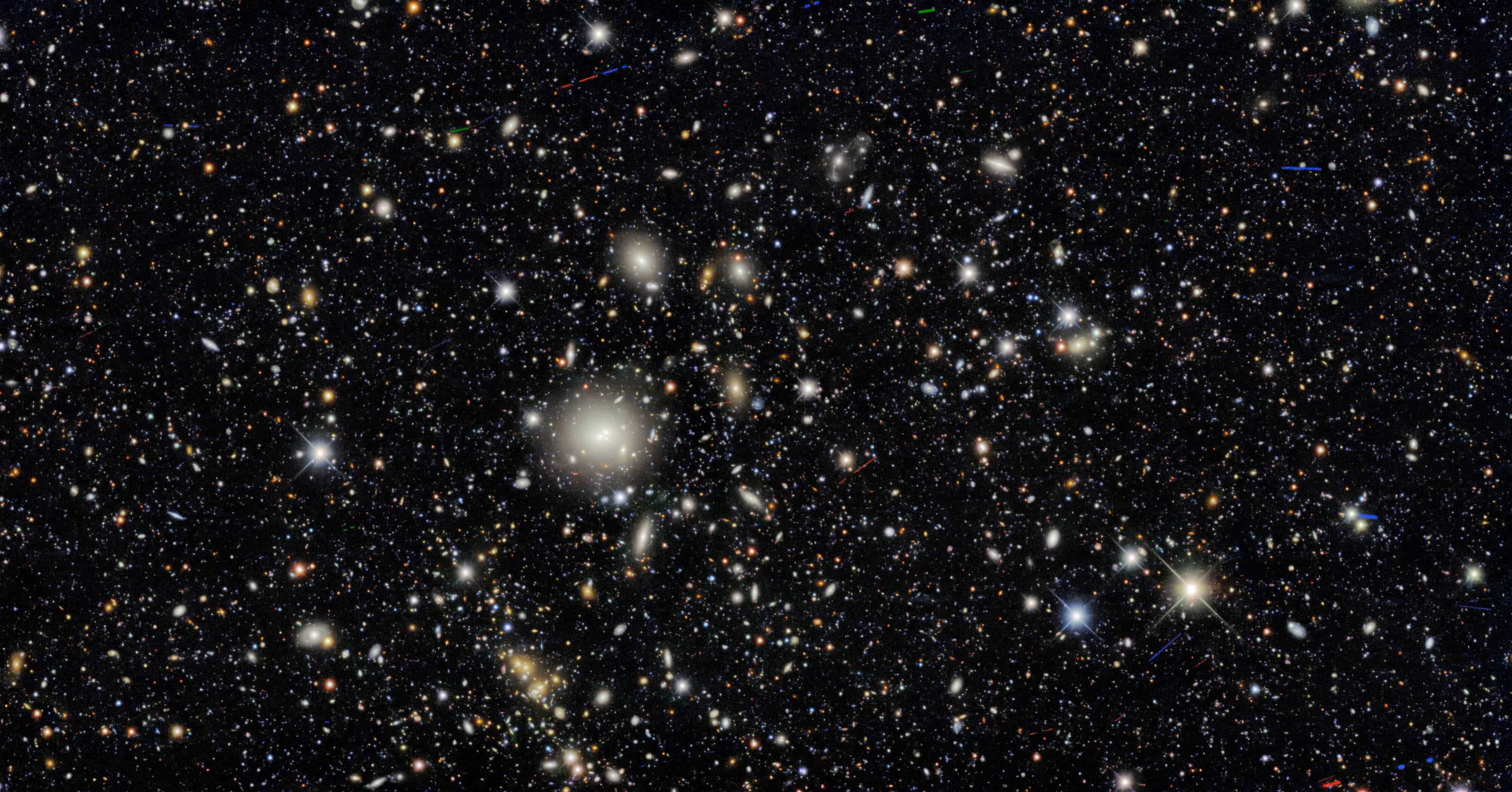 Dark Energy Survey deep field: a black sky densely packed with small galaxies, a bright elliptical galaxy near the centre and a few foreground stars.