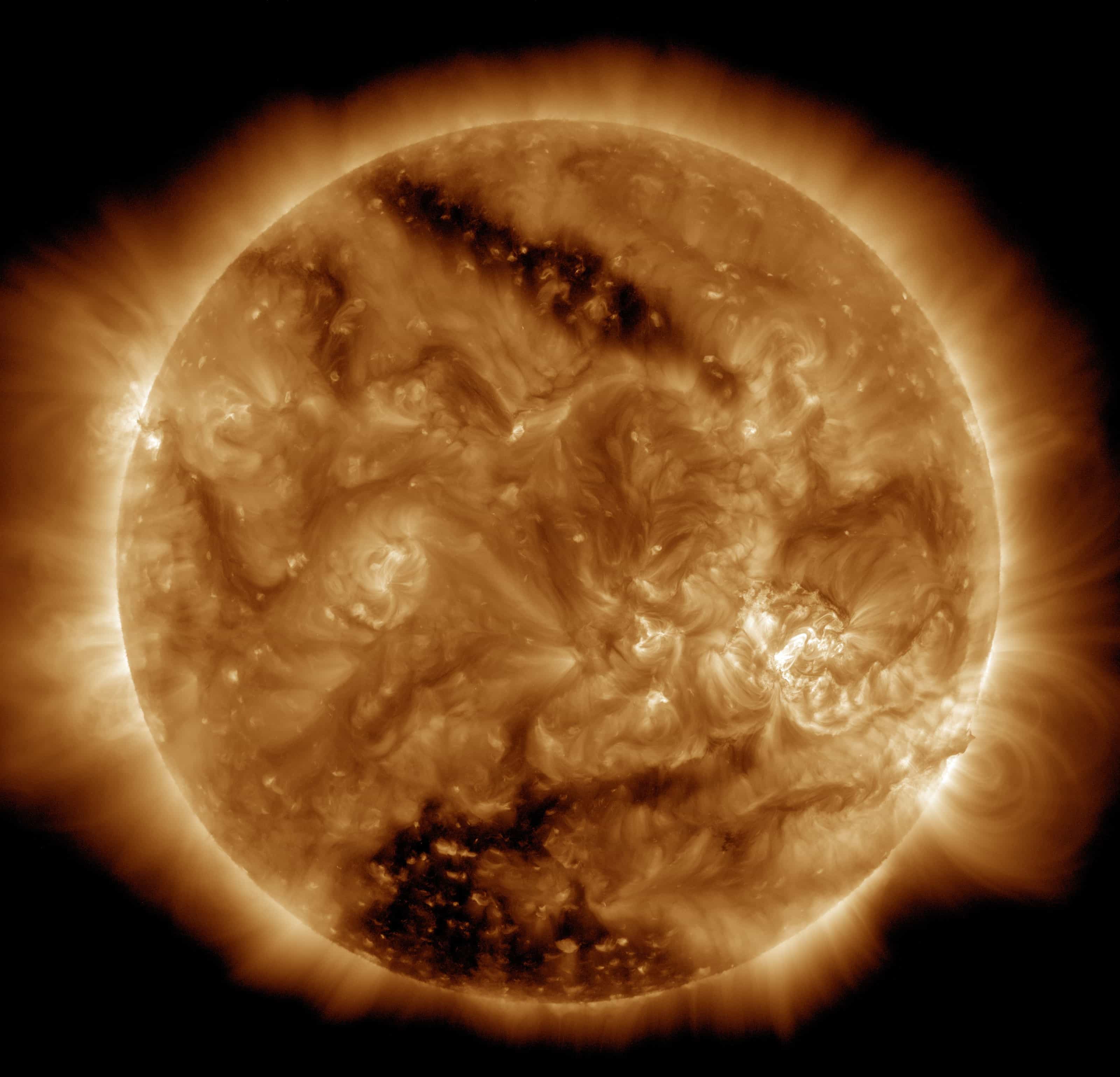 The Sun in extreme ultraviolet light from NASA's Solar Dynamics Observatory, 16 March 2015: a golden disk laced with glowing loops, with two large dark coronal holes near the top and bottom.