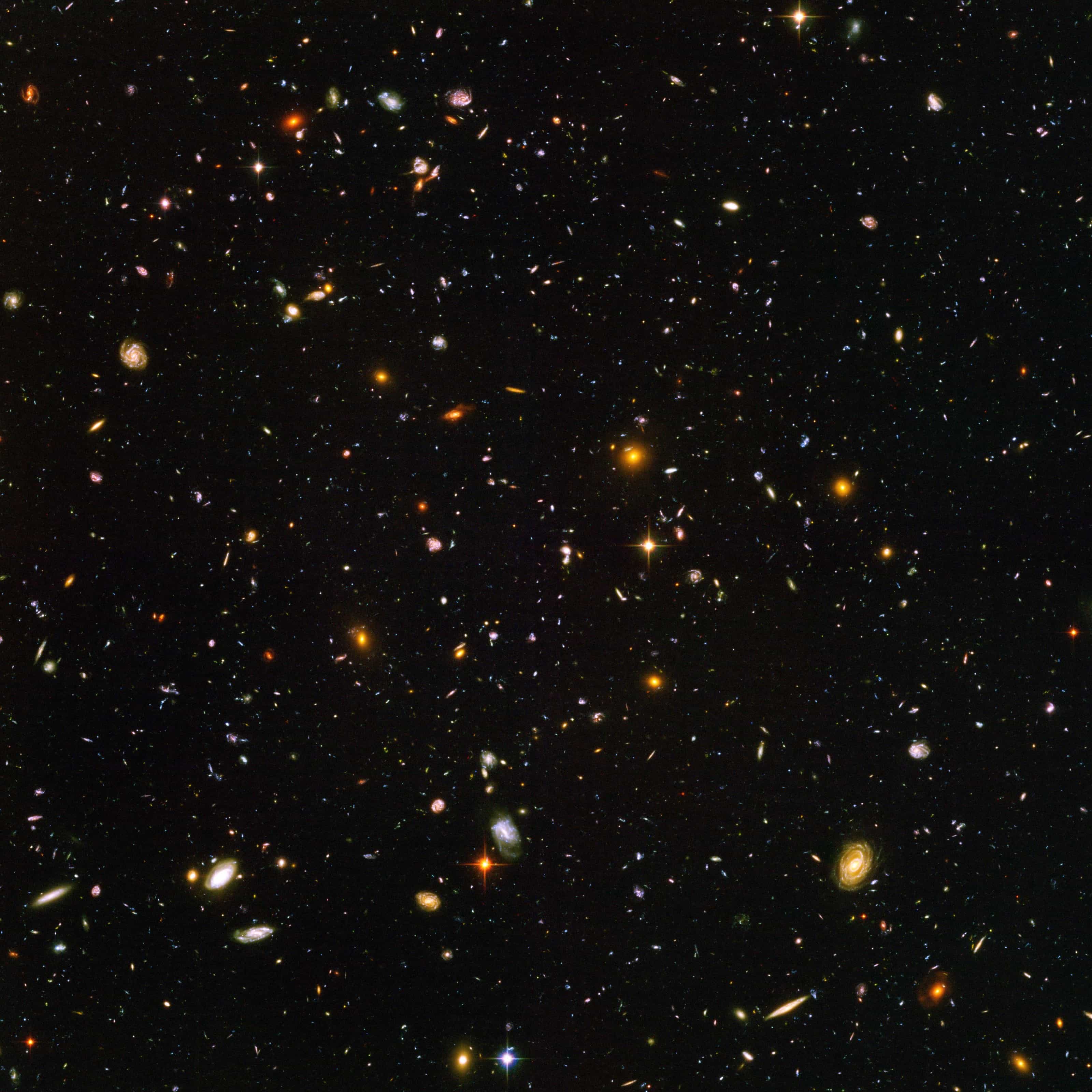 The Hubble Ultra Deep Field: a tiny patch of sky filled with thousands of galaxies of many shapes and colours on a black background.